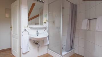 Un baño con lavamanos blanco, espejo y ducha.