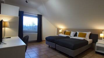 Quarto de hotel com uma cama, duas mesas de cabeceira, uma escrivaninha e uma cadeira.