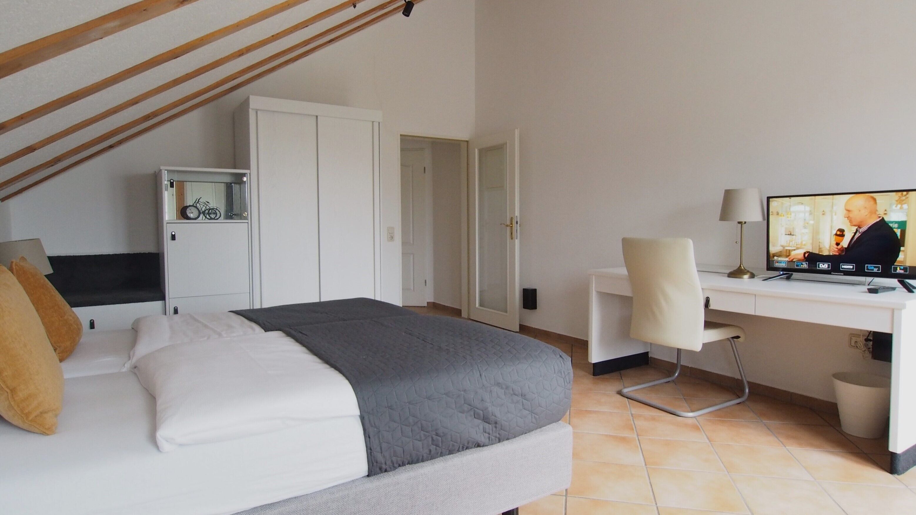 Une chambre d’hôtel comprenant un lit, un bureau, une chaise, une télévision et une armoire.