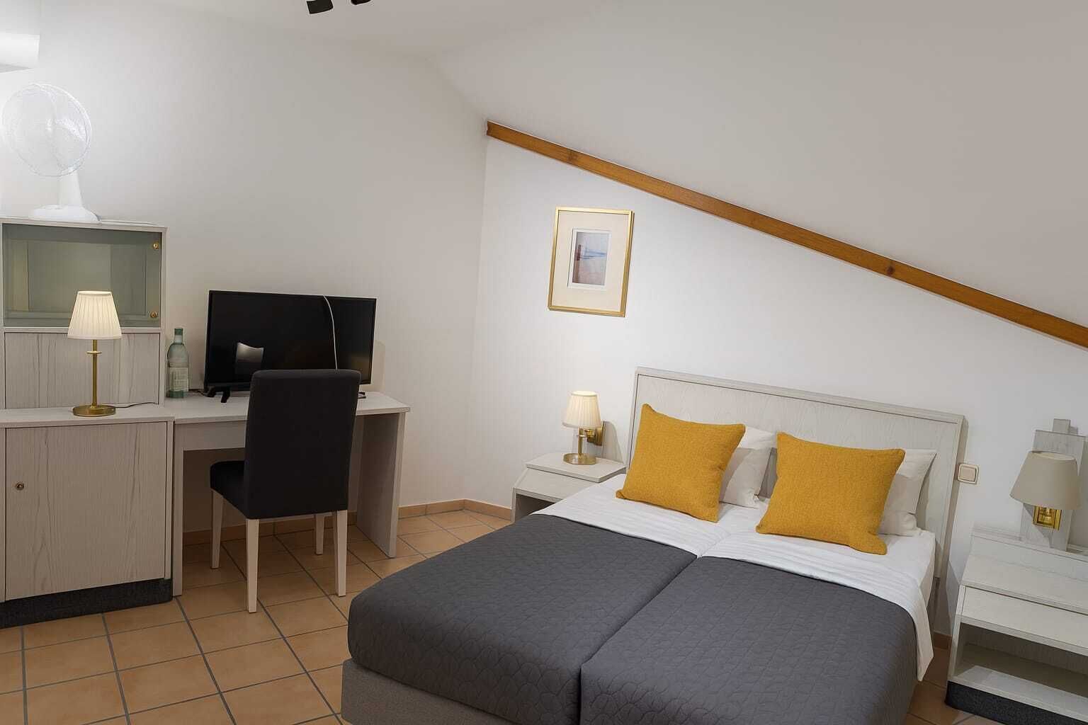 Habitación de hotel con cama, escritorio, silla y televisor.