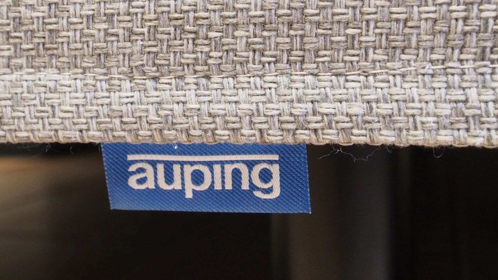 A close-up of a woven fabric with a blue tag labeled "auping".