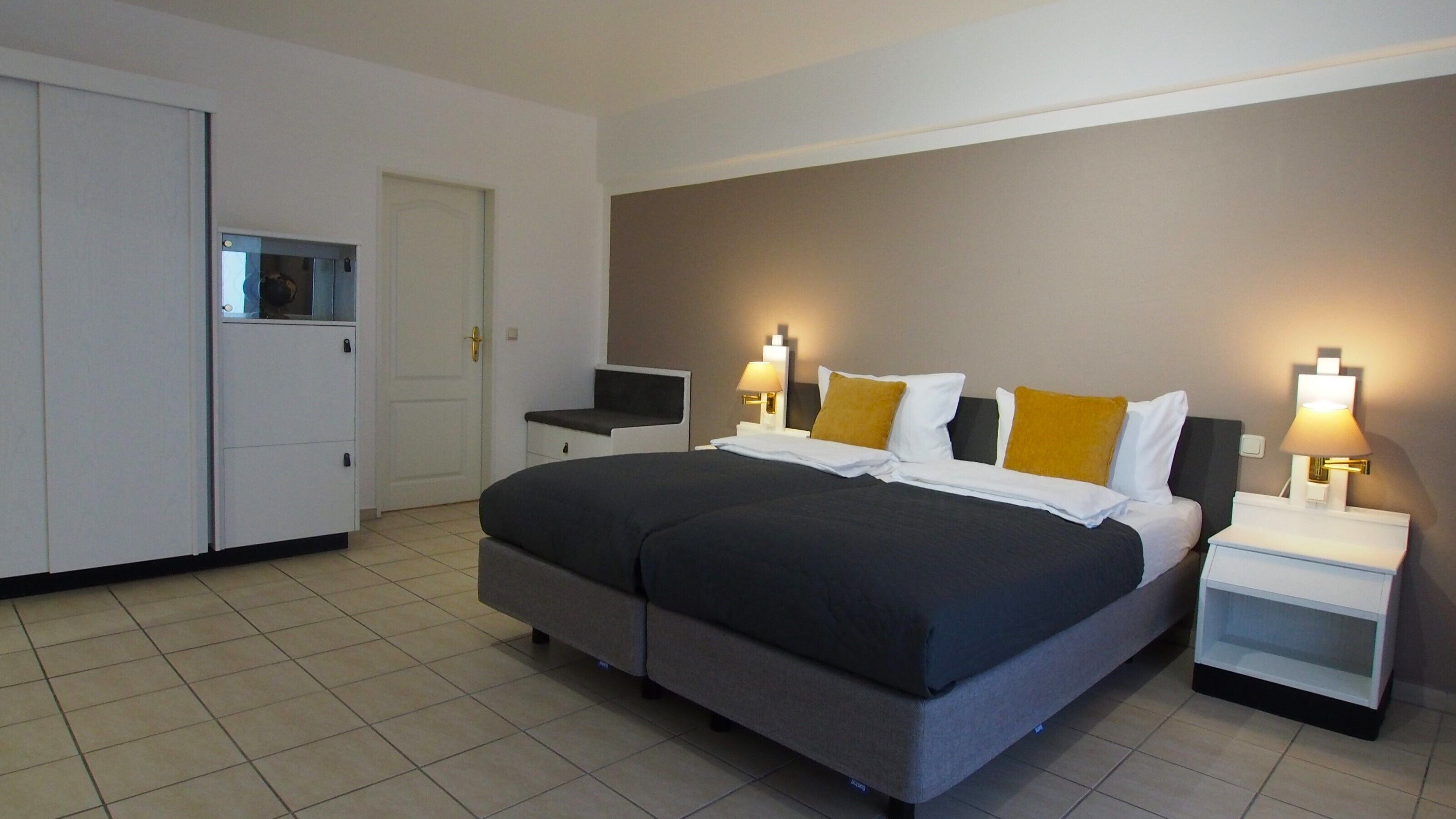 Una habitación de hotel moderna con una cama grande, mesitas de noche, un escritorio y un armario.