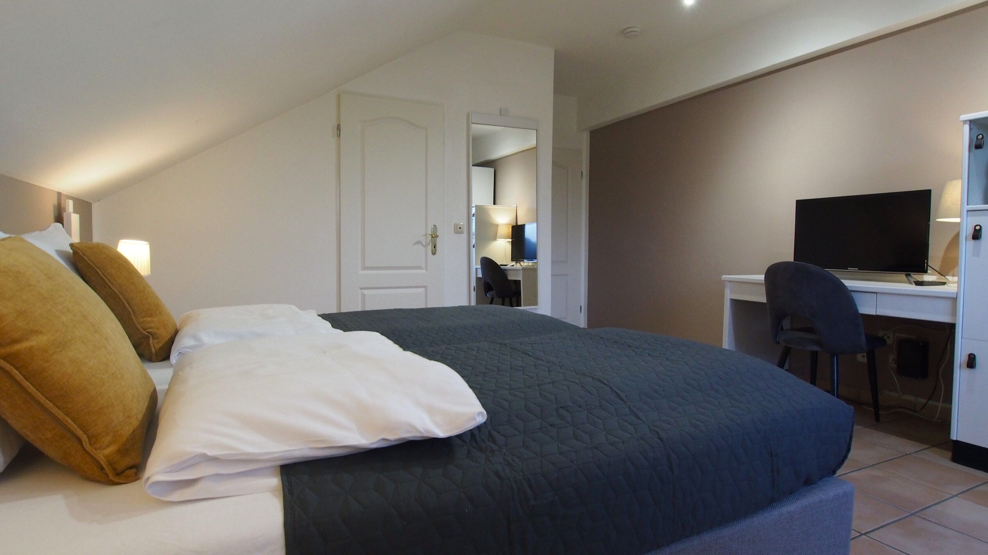Una habitación de hotel con una cama, un escritorio y un televisor.