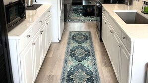 Een compacte kitchenette met een koelkast, magnetron, spoelbak en koffiezetapparaat.