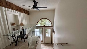 A staircase with a glass railing, a ceiling fan, and a door with a window above it.