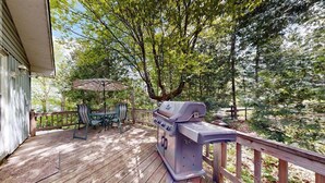 A wooden deck with a grill, outdoor table, and chairs.