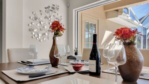 Una mesa de comedor servida con platos, cubiertos, copas de vino y jarrones con flores.
