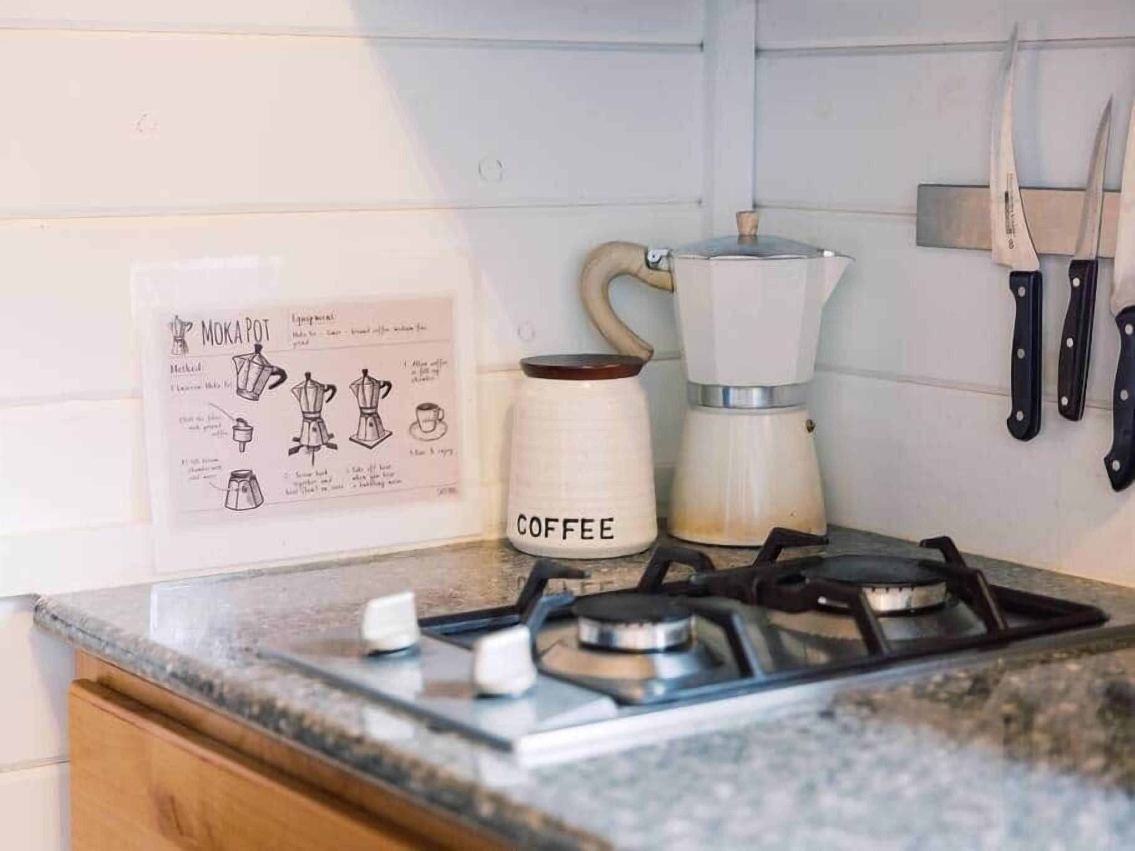 A kitchen with a coffee maker, a gas stove, and a wall-mounted knife rack.