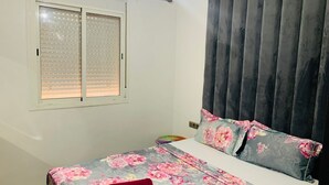 Ein Schlafzimmer mit einem Bett, einem Fenster mit Jalousien und einem Vorhang.