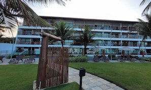 A hotel with a multi-story building, outdoor seating area, and palm trees.