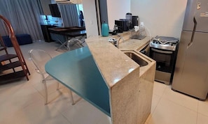 Una cocina con encimera de granito, un fregadero, una estufa y un refrigerador.