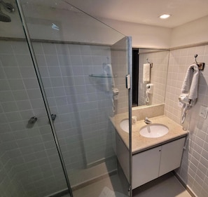 Un baño moderno con cabina de ducha de vidrio, tocador doble y toallero.