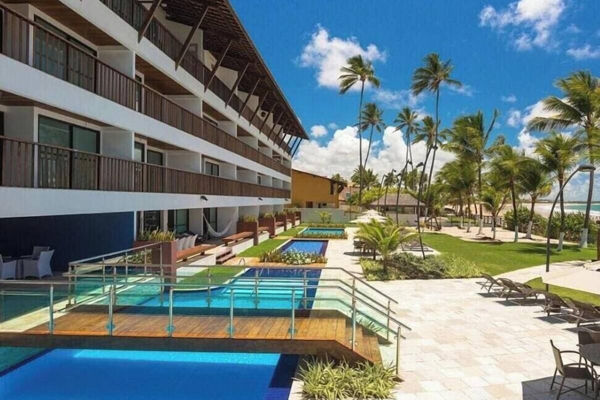 Un hotel con varios balcones, una zona de piscina y palmeras.
