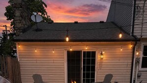 A backyard patio with a fire pit, outdoor furniture, and string lights. - Lake Escape-Pool Table-Kids Game Room-Wii-Foosball (Avon Lake)