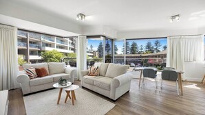 A modern living room with two sofas, a coffee table, and a dining area with chairs. Large windows provide a view of the outside. - Sunlit Durham Walk to Glenelg Beach Dining and Bars (Glenelg)