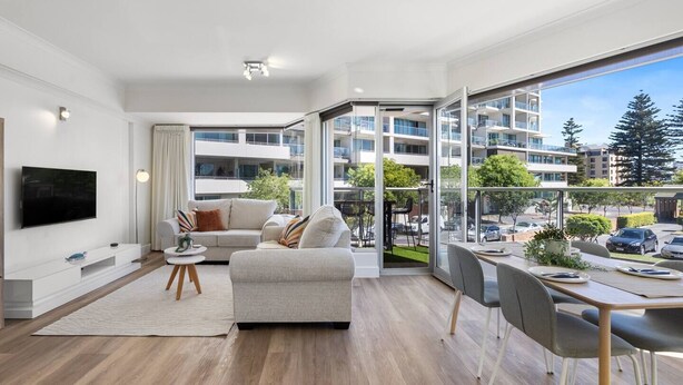 A modern apartment with a living room, dining area, and balcony with a city view. - Sunlit Durham Walk to Glenelg Beach Dining and Bars (Glenelg)
