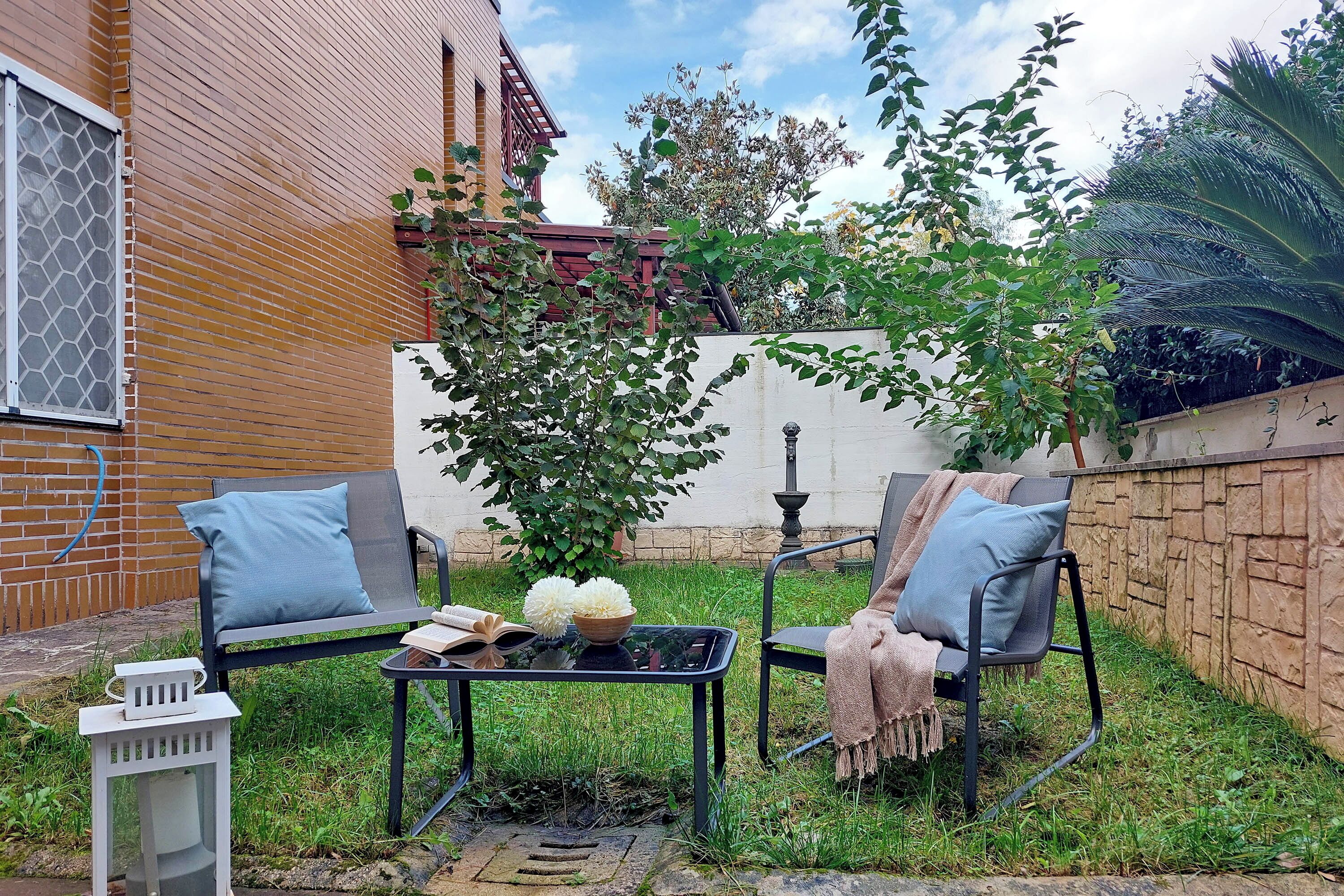 Uma área externa com assentos para dois, uma mesa e um candeeiro.