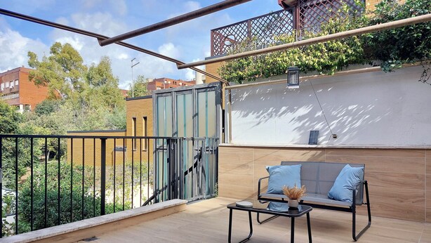 Un balcon avec un canapé, une petite table et une plante en pot.