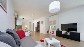 Un salon moderne avec un canapé, un téléviseur et un coin repas.