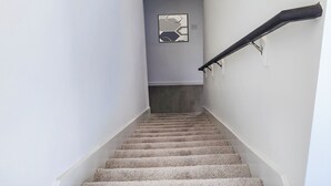 A staircase with a handrail, carpeted steps, and two framed artworks on the walls. - Peaceful 4-bedroom house in charming Katy, Near Energy Corridor, Lagoon, parks. (Katy)