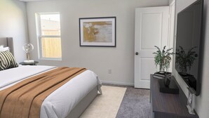 A bedroom with a bed, a bedside table with a lamp, a framed artwork on the wall, a door, and a TV mounted on the wall. - Peaceful 4-bedroom house in charming Katy, Near Energy Corridor, Lagoon, parks. (Katy)