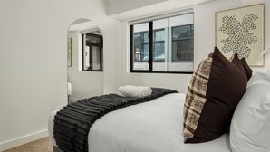 Ein modernes Hotelzimmer mit einem ordentlich bezogenen Bett, einem großen Fenster und Blick nach außen.