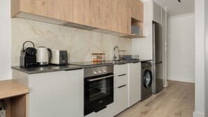 A modern kitchen with a built-in oven, microwave, and washing machine. - The York | Designer CBD Apartment (Cape Town)