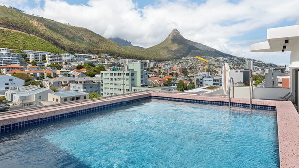 A swimming pool with a view of a cityscape and a mountain in the background. - Coastal Studio in the Heart of Sea Point | Pool (Cape Town)
