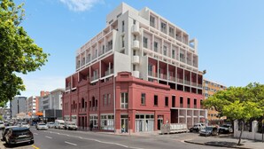 A multi-story building with a modern architectural design, featuring balconies and large windows. - Coastal Studio in the Heart of Sea Point | Pool (Cape Town)