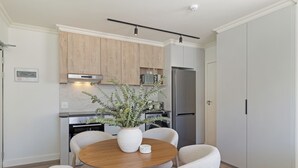 Eine moderne Küche mit Holzausstattung, einem Edelstahlkühlschrank und einem Esstisch mit Stühlen.