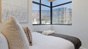 Ein Schlafzimmer mit großem Fenster und Blick auf die Stadt.