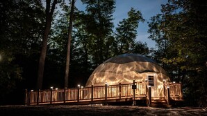 A dome-shaped structure with a wooden deck and railing, surrounded by trees. - Lakeside Calm at Dimensions | Cabin One | Breakfast Included (Algonquin Highlands)