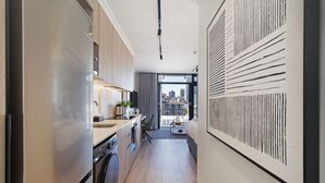 A modern kitchen with a stainless steel refrigerator, wooden cabinets, and a built-in washing machine. - Cosy Studio Apartment | The York (Cape Town)