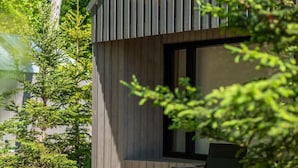Een modern gebouw met een houten terras en een bankje.