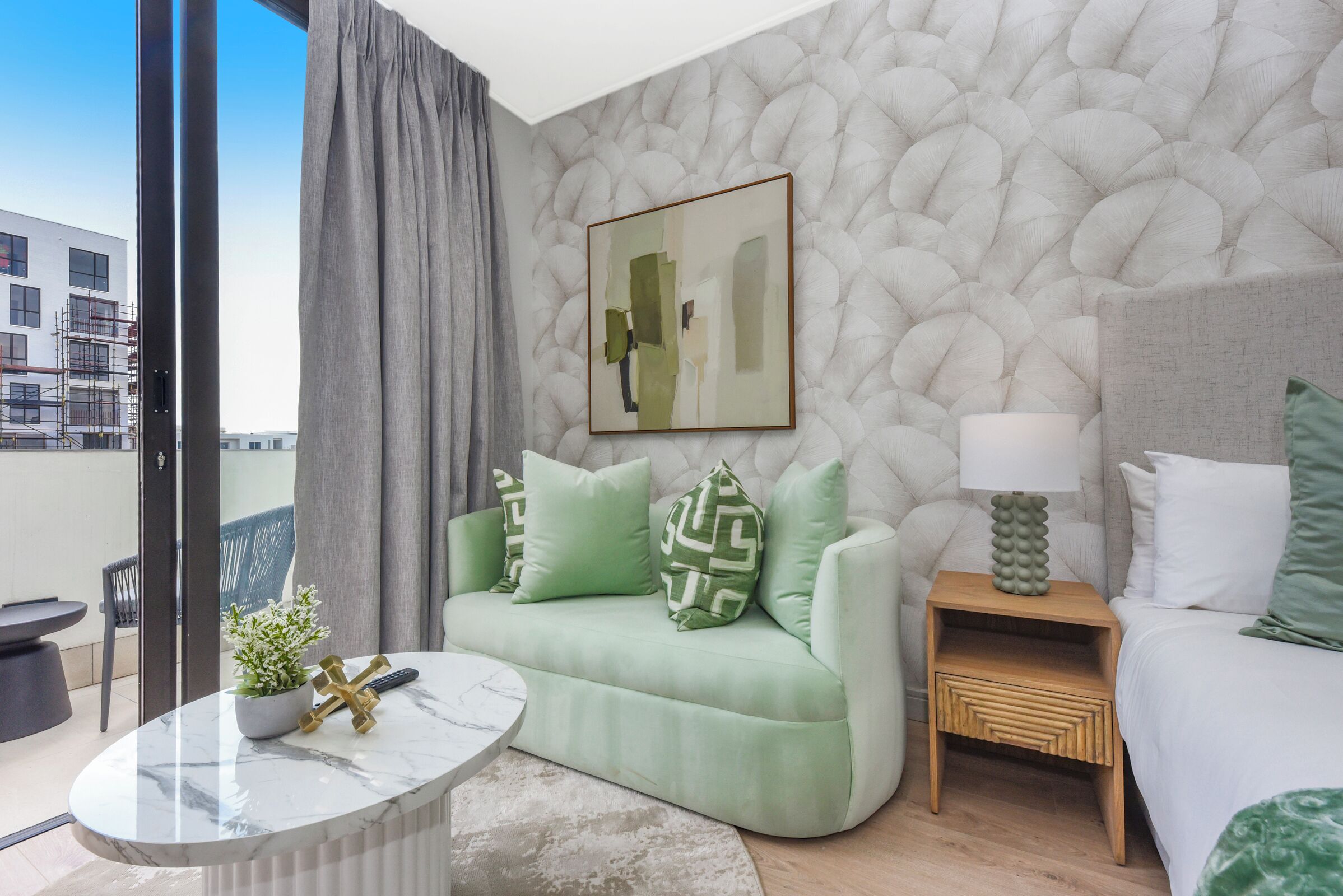 Una sala de estar moderna con un sofá verde, una mesa de centro de mármol y una mesita de noche de madera.