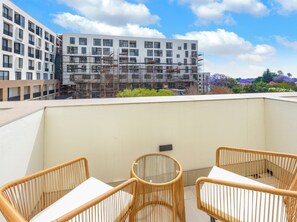 Terraço no telhado com cadeiras de vime e uma mesa, com vista para um edifício em construção com andaimes.