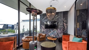 A modern living room with leather sofas, a round coffee table, and a fireplace. - The Velvet Touch | One Rosebank Studio (Johannesburg)