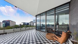 A modern balcony with a checkered floor, large glass doors, and a view of the cityscape. - The Velvet Touch | One Rosebank Studio (Johannesburg)