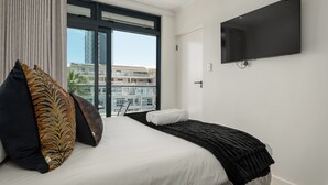 Ett modernt hotellrum med en stor säng, en platt-TV och en balkong med utsikt över staden.