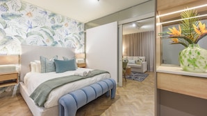 Un dormitorio moderno con una cama grande, una mesita de noche, un banco, un tocador y un espejo.