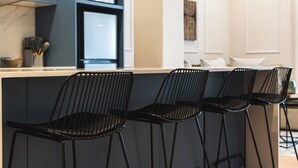 A modern kitchen with a bar area featuring black metal chairs. - Modern Venetian Elegance in CBD (Cape Town)