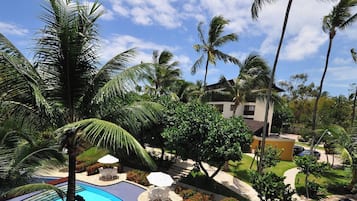 Um resort com piscina, palmeiras e um edifício com varandas.