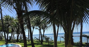A pool surrounded by palm trees and a view of the ocean. - Nannai Residence (Ipojuca)