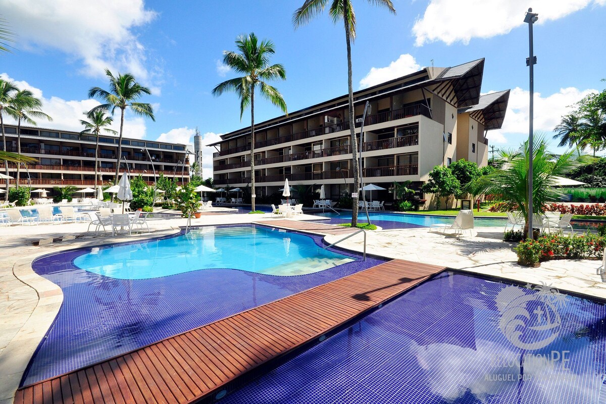 Ein Hotel mit Swimmingpool, Palmen und einem mehrstöckigen Gebäude.