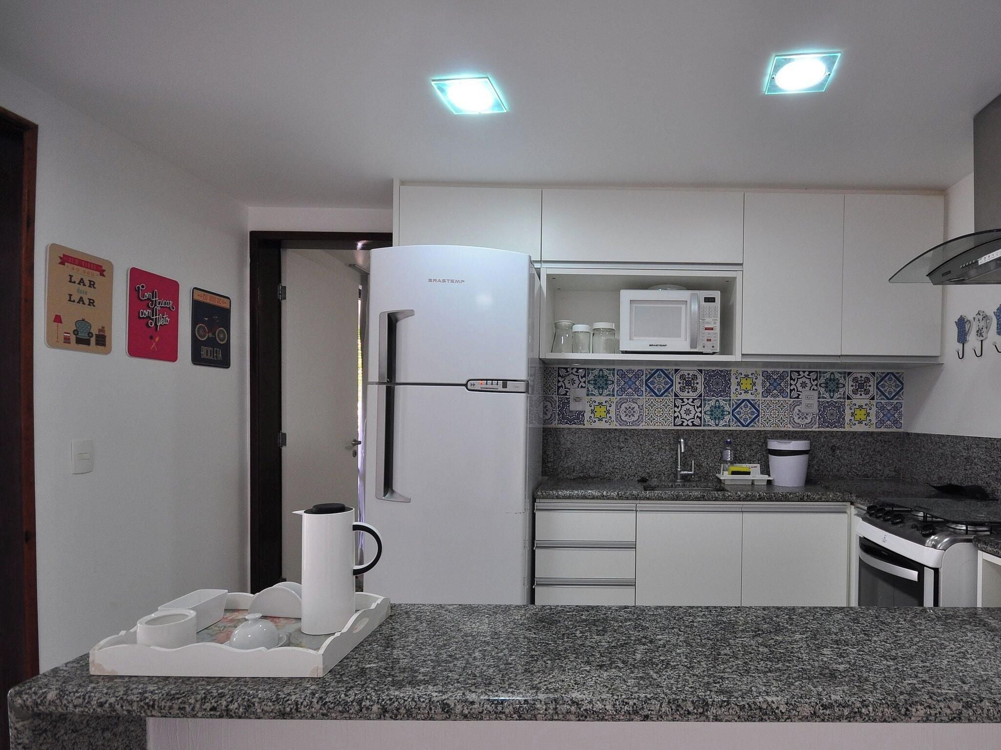 A kitchen with a refrigerator, microwave, stove, and granite countertop.