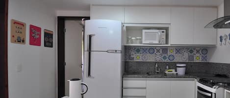 A kitchen with a refrigerator, microwave, stove, and granite countertop.