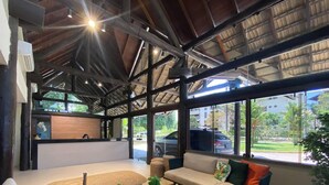 Um hall amplo com balcão de recepção, sofá e grandes janelas com vista para o exterior.