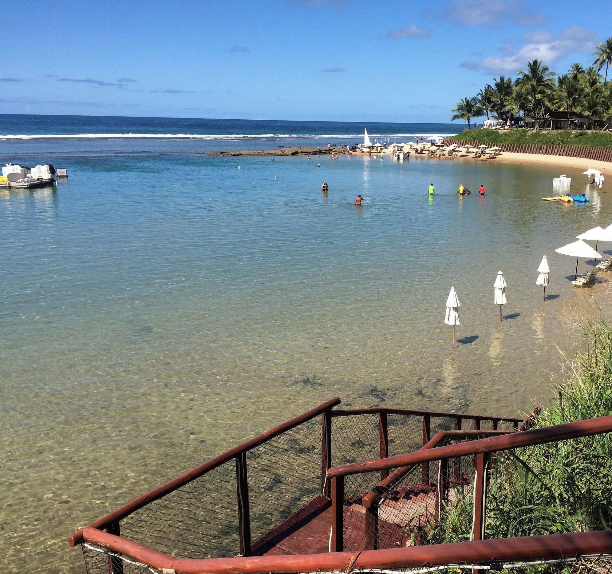 A beach with clear water, a sandy shore, and a few umbrellas.