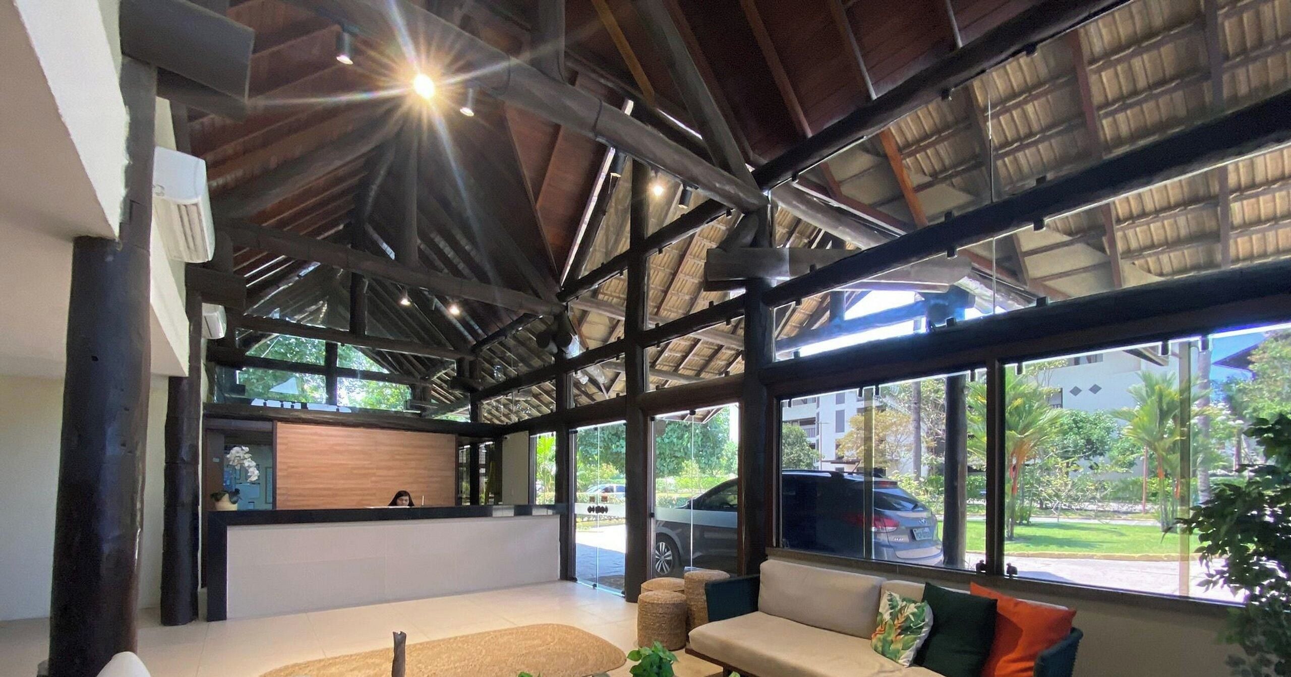 Amplo espaço interno com teto alto, grandes janelas e um balcão de recepção.