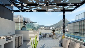 En tagterrasse med et moderne udendørs køkken, siddepladser og krukker med planter.
